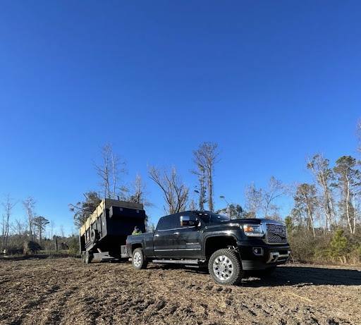 Dump truck and trailer clearing debris from a commercial lot.